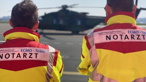 Notärzte stehen vor einem Rettungshubschrauber.