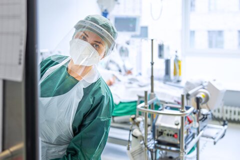 Intensivpflegerin schaut aus Patientenzimmer heraus in den Krankenhausflur.