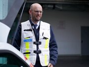 Leitender Notarzt steht neben Einsatzfahrzeug.